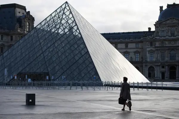 Un peatón cruza el patio vacío fuera del Museo del Louvre durante la hora punta de la mañana en París, Francia, el lunes 2 de noviembre de 2020.