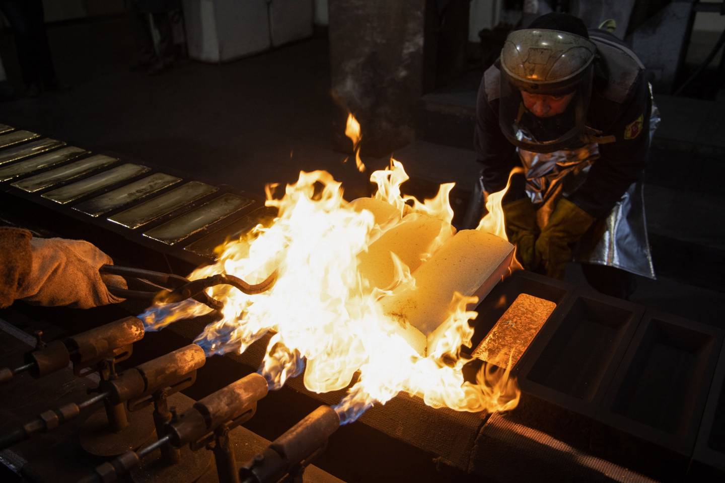 Las llamas encienden lingotes de oro recién vertidos en sus moldes en una fundición en Kasimov, Rusia