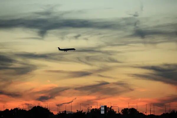 Imagem do céu, durante o pôr-do-sol, mostrando um avião em voo